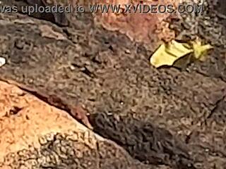 Uma linda novinha é observada fazendo sexo em público nas pedras da praia e é atrapalhado por um terceiro indivíduo