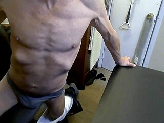 Grinding on stool and football in grey briefs for muscle tension release